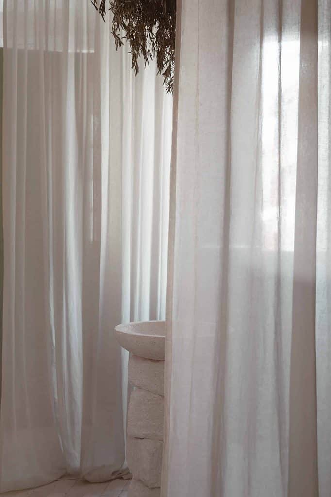 Background image. Flowy curtatins over a window and light streaming in